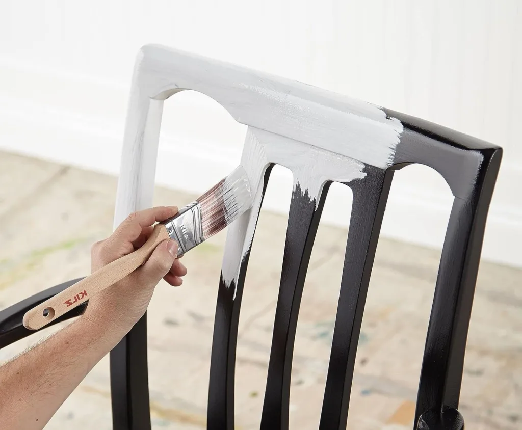 Man priming his wood chair with bonding primer before he paints it.
